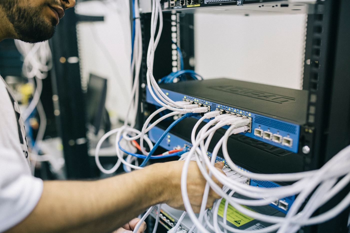 Técnico a configurar cabos de rede em rack de servidor